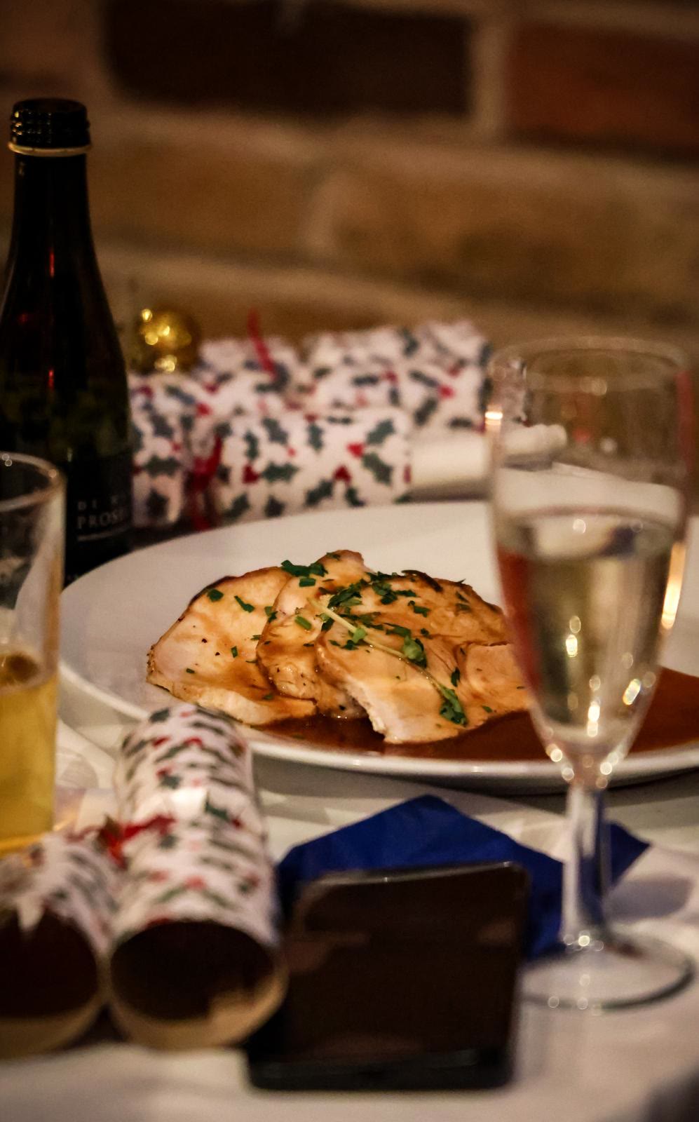 Festive table with roast turkey, glasses of prosecco and crackers